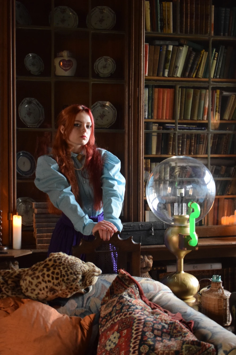 A Victorian character photographed in a library beside a fantastical glass device